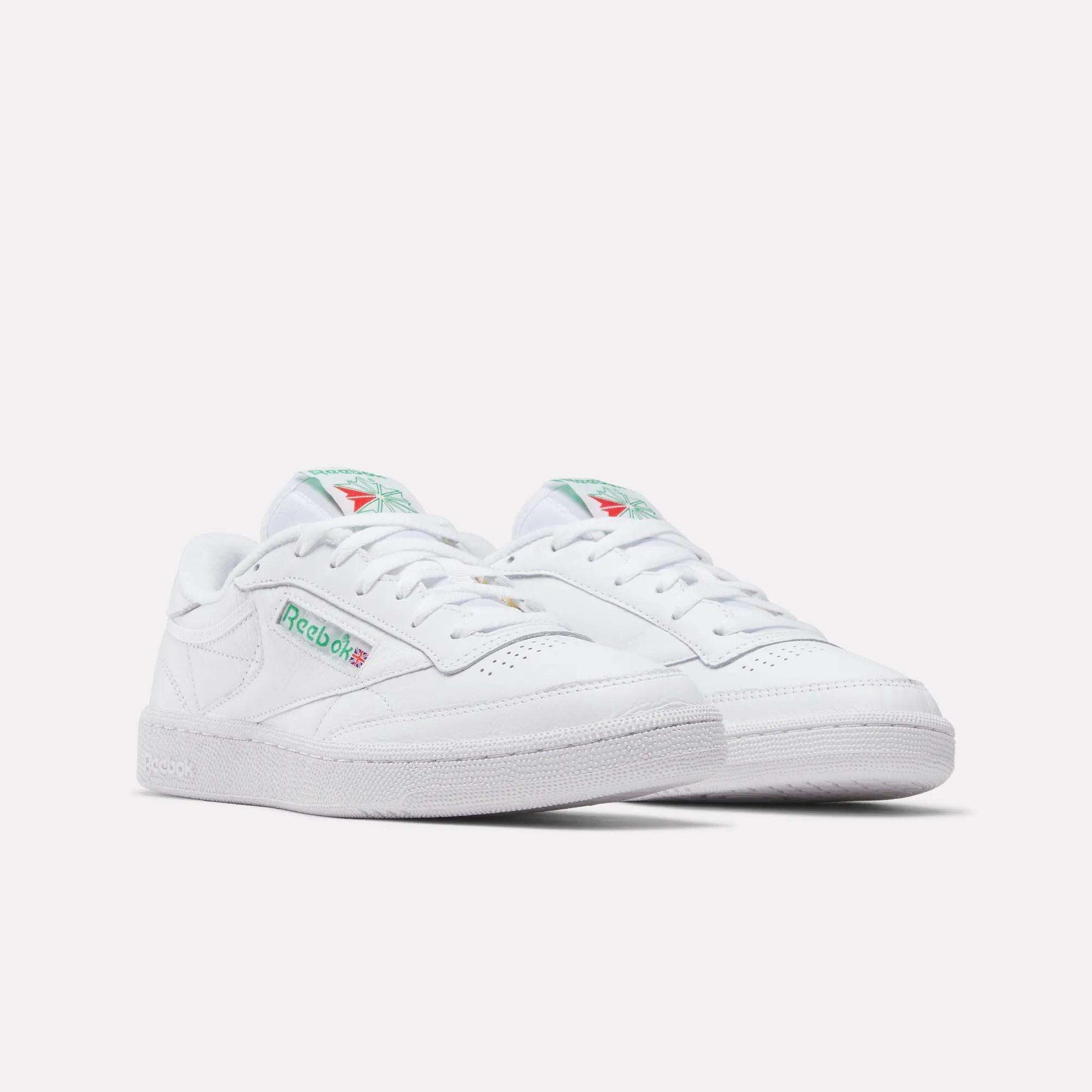 A pair of Reebok Club C 85 Shoes in white leather with green and red logo accents, shown on a plain white background. These tennis-inspired sneakers have a classic low-top design and perforated toe detailing.