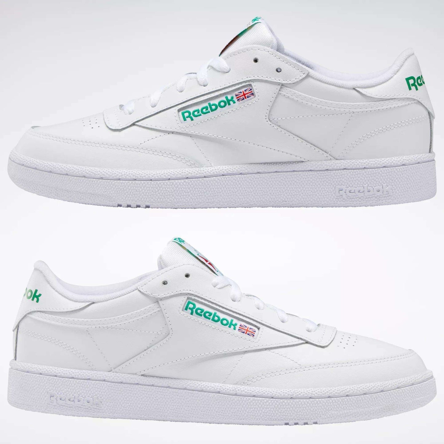 Two white Reebok Club C 85 Shoes are shown in profile, featuring green logos and Union Jack flag details on the sides, set against a plain white background to highlight their classic, tennis-inspired design.