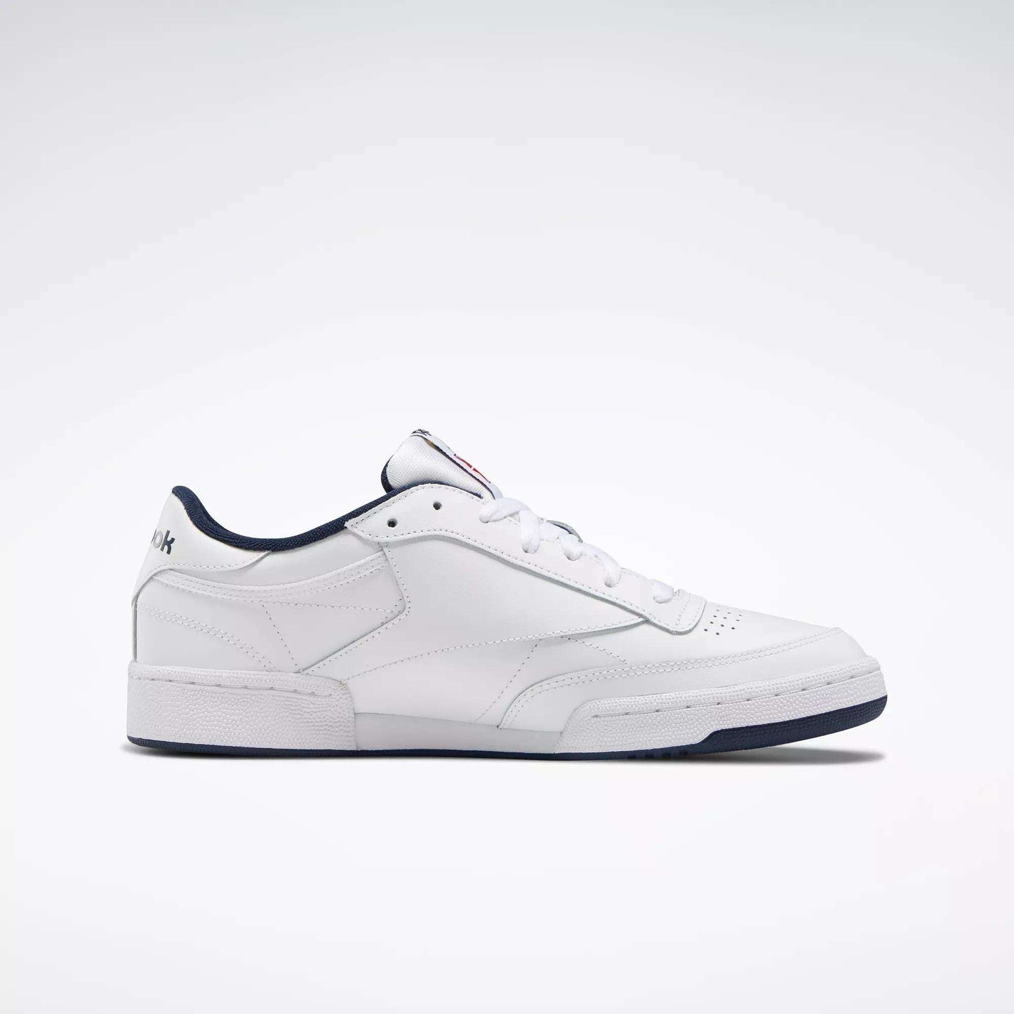 The Reebok Club C 85 Shoes are white low-top leather sneakers inspired by classic tennis style, featuring a dark blue sole and trim, simple stitching, and subtle branding on the heel and tongue.