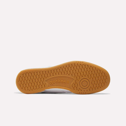 The image displays the sole of Reebok Club C 85 Shoes, with light brown rubber, a herringbone tread pattern, a circular front detail, and the Reebok logo embossed at the center—classic elements of tennis-inspired footwear.
