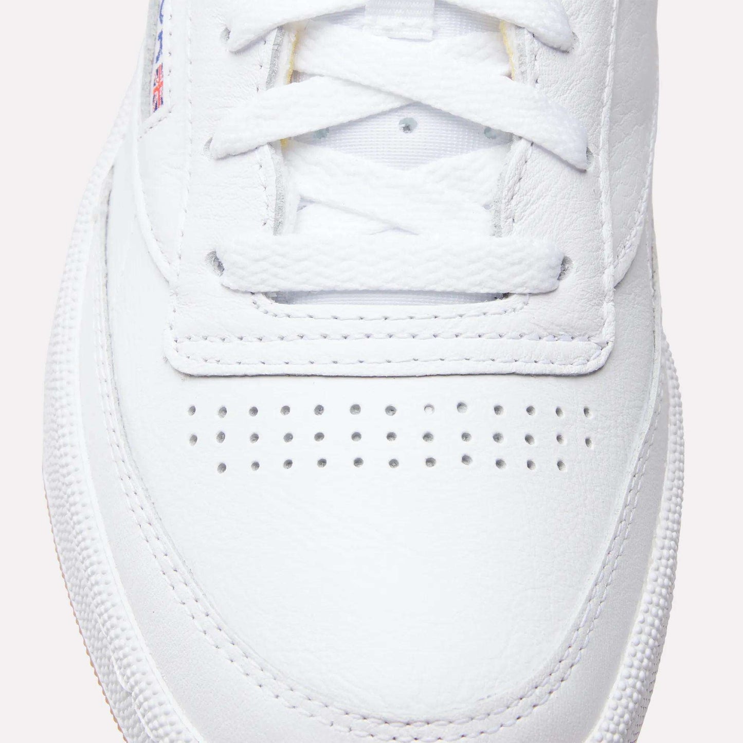Close-up of the toe box and laces on Reebok Club C 85 Shoes, highlighting their textured leather upper, breathable perforations, and part of the rubber sole inspired by classic tennis style.