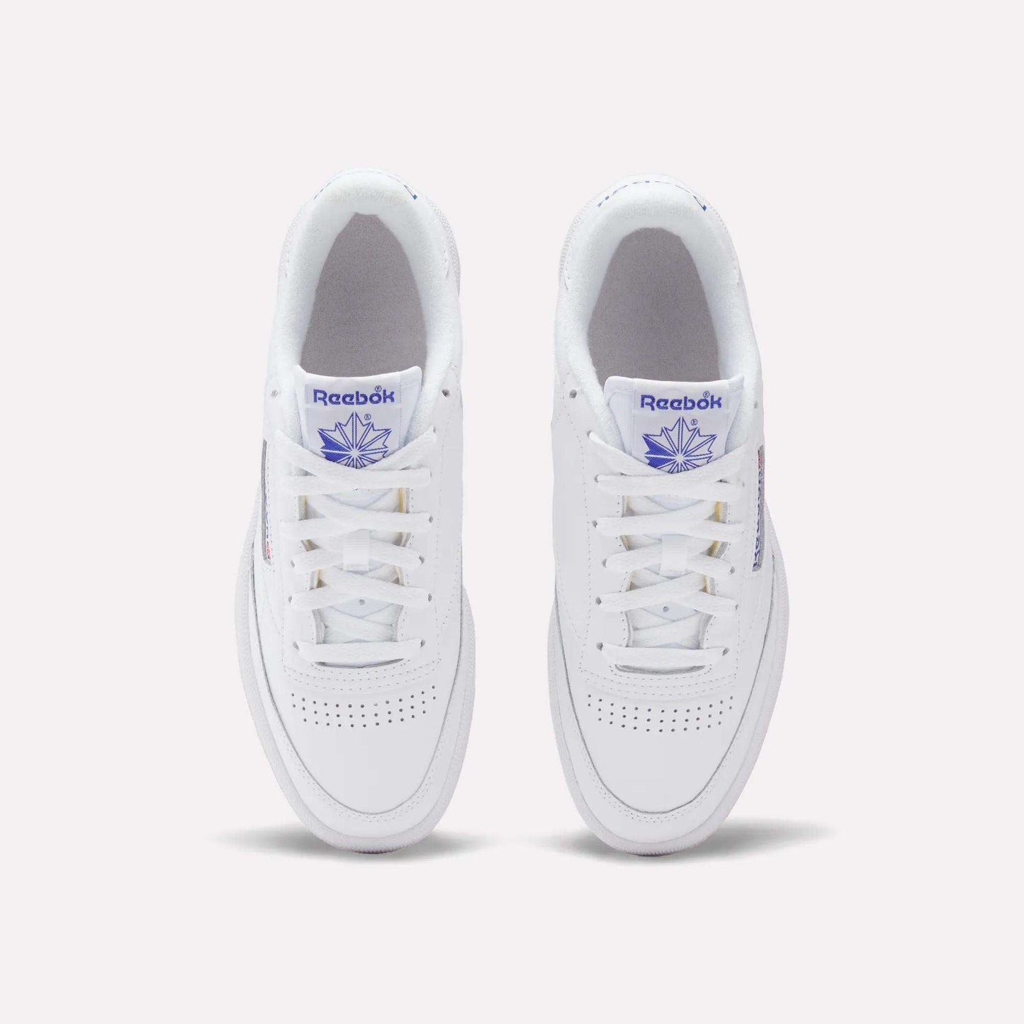 A top view of Reebok Club C 85 Shoes in white leather, featuring purple Reebok branding on the tongue and side, classic white laces, and perforated toe detailing for a timeless tennis-inspired style.