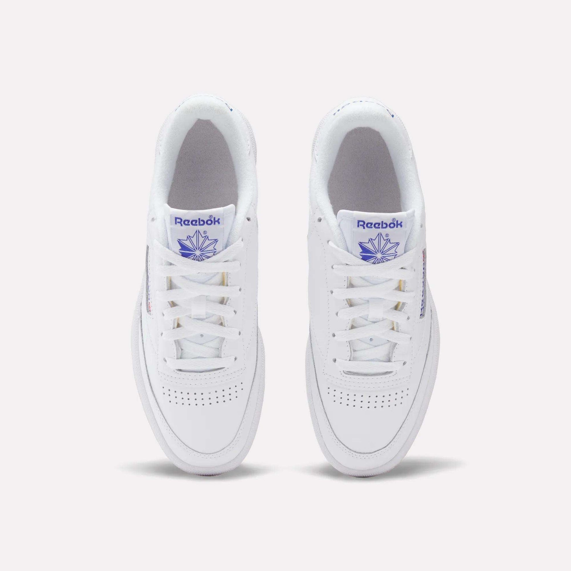 A top view of Reebok Club C 85 Shoes in white leather, featuring purple Reebok branding on the tongue and side, classic white laces, and perforated toe detailing for a timeless tennis-inspired style.