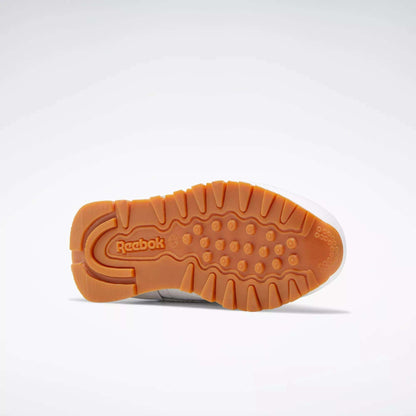 The image shows the sole of the Reebok Kids' Classic Leather Shoes - Preschool, featuring a textured orange rubber outsole with circular grip patterns and the Reebok logo. This lightweight shoe is shown on a plain white background.