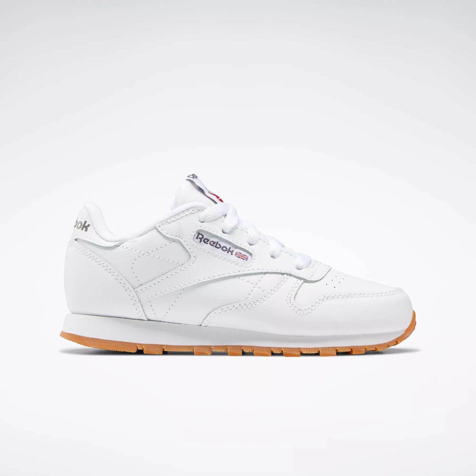 The Reebok Kids' Classic Leather Shoes - Preschool are shown in profile with a white leather upper, gum sole, white laces, stitching details, and the Reebok logo with a Union Jack flag on the side against a plain light background.