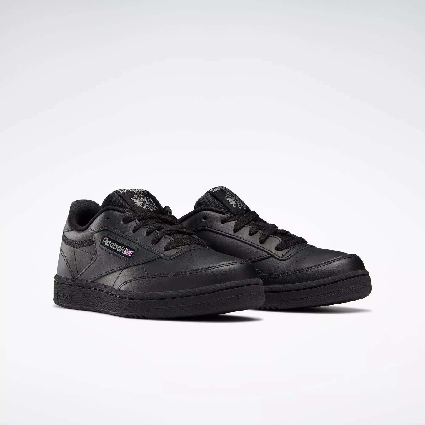 A pair of Reebok Kids' Club C Shoes - Grade School with black leather uppers, black soles and laces, the Reebok logo and a small Union Jack on the side, displayed on a plain white background.