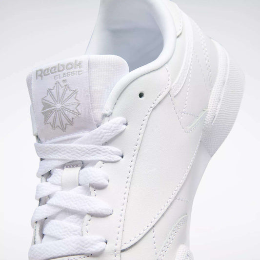 Close-up of the Kids' Club C Shoes - Grade School by Reebok, featuring white soft leather uppers, detailed stitching, laces, a branded tongue with logo and starburst, plus a high-abrasion rubber outsole.