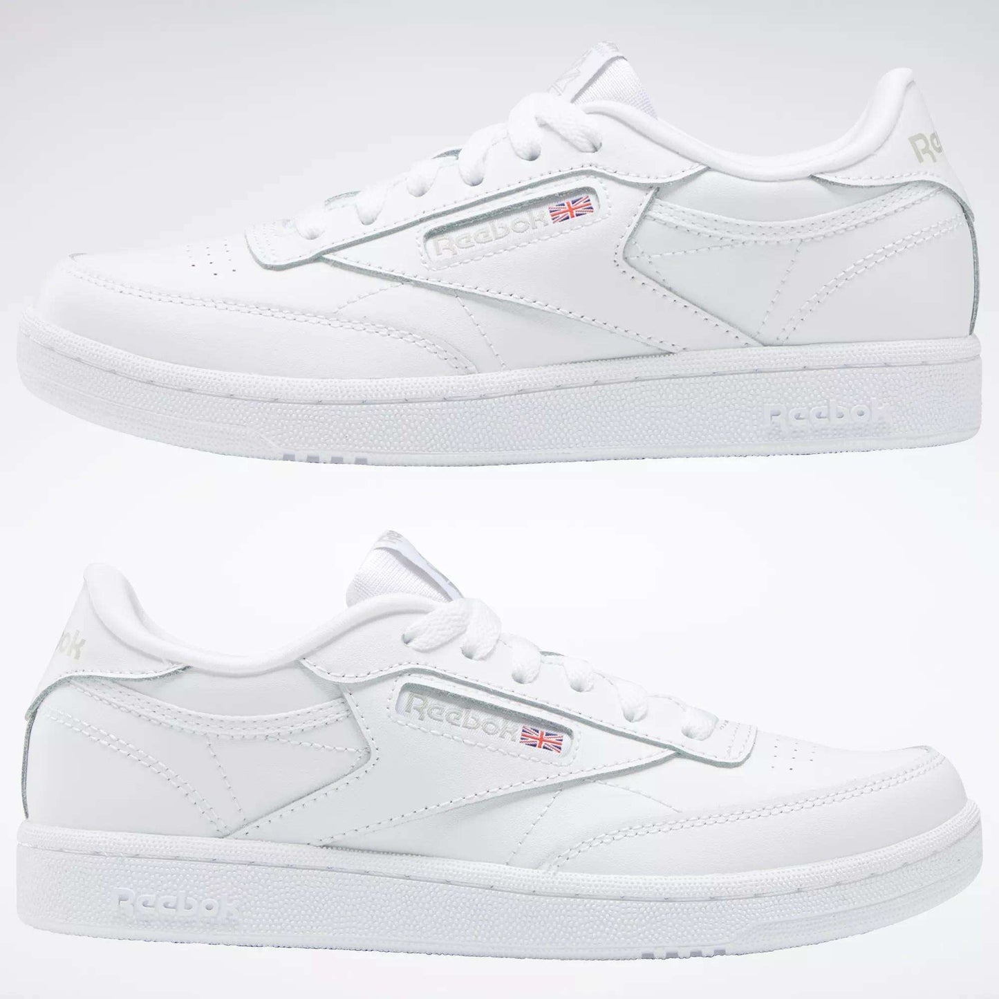 Two white Reebok Kids' Club C Shoes for grade school are shown side by side, highlighting soft leather uppers, subtle Reebok branding with the Union Jack flag, stitching details, and a plain light-colored background.