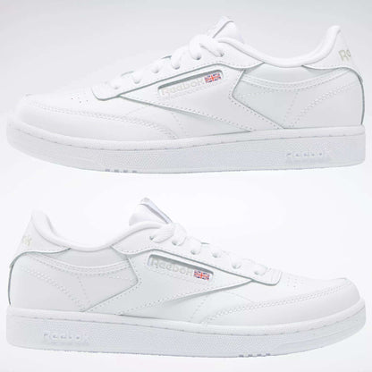 Two white Reebok Kids' Club C Shoes for grade school are shown side by side, highlighting soft leather uppers, subtle Reebok branding with the Union Jack flag, stitching details, and a plain light-colored background.
