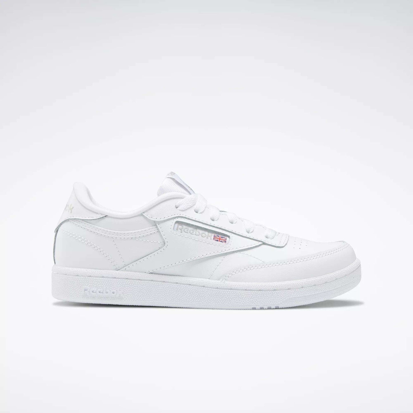 The Kids' Club C Shoes – Grade School by Reebok are white low-top sneakers with soft leather uppers, the Reebok logo, and a small Union Jack flag on the side, shown on a plain white background.