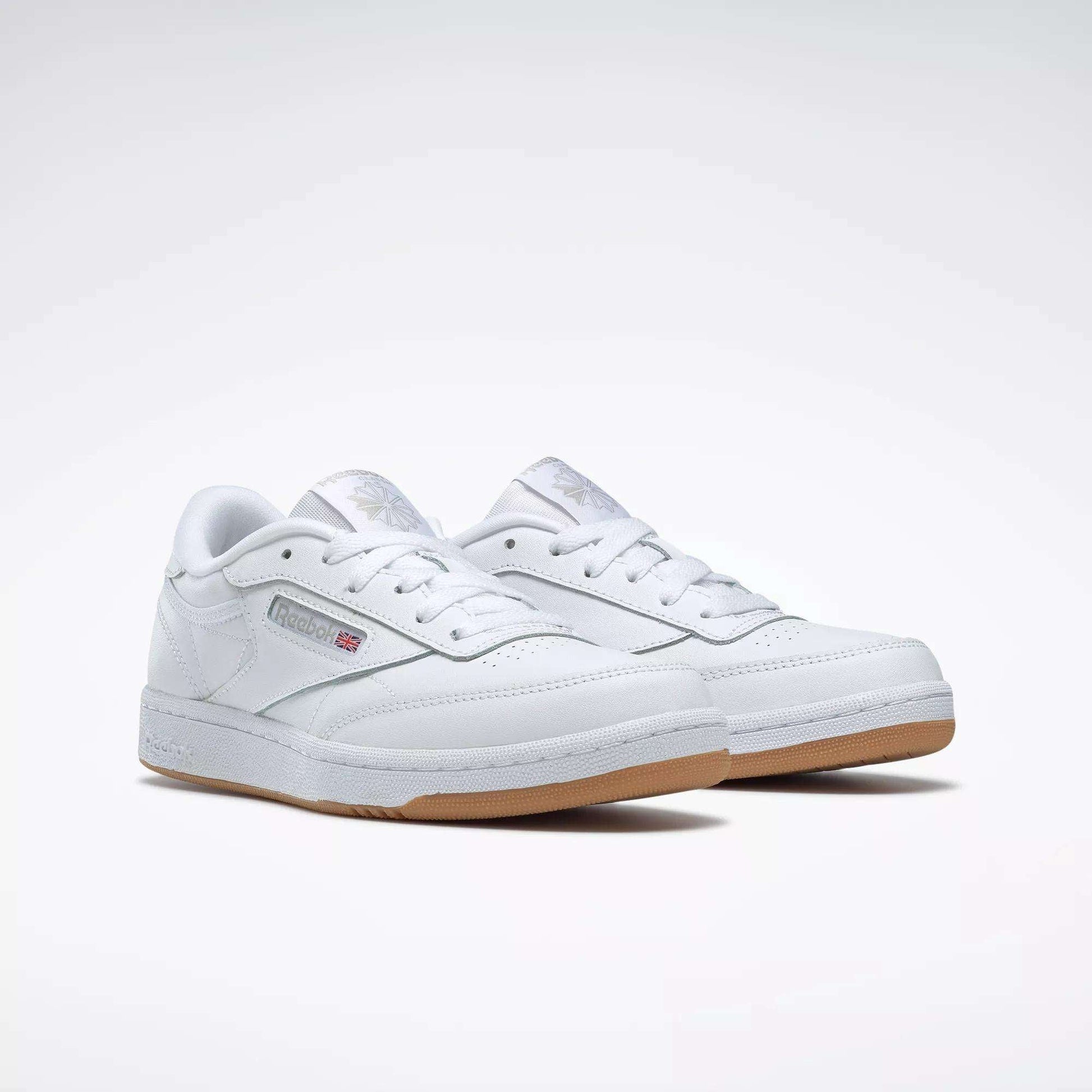 The Reebok Kids' Club C Shoes - Grade School feature classic white soft leather uppers, gum soles, and display the Reebok logo with a British flag on the side, shown against a plain white background.