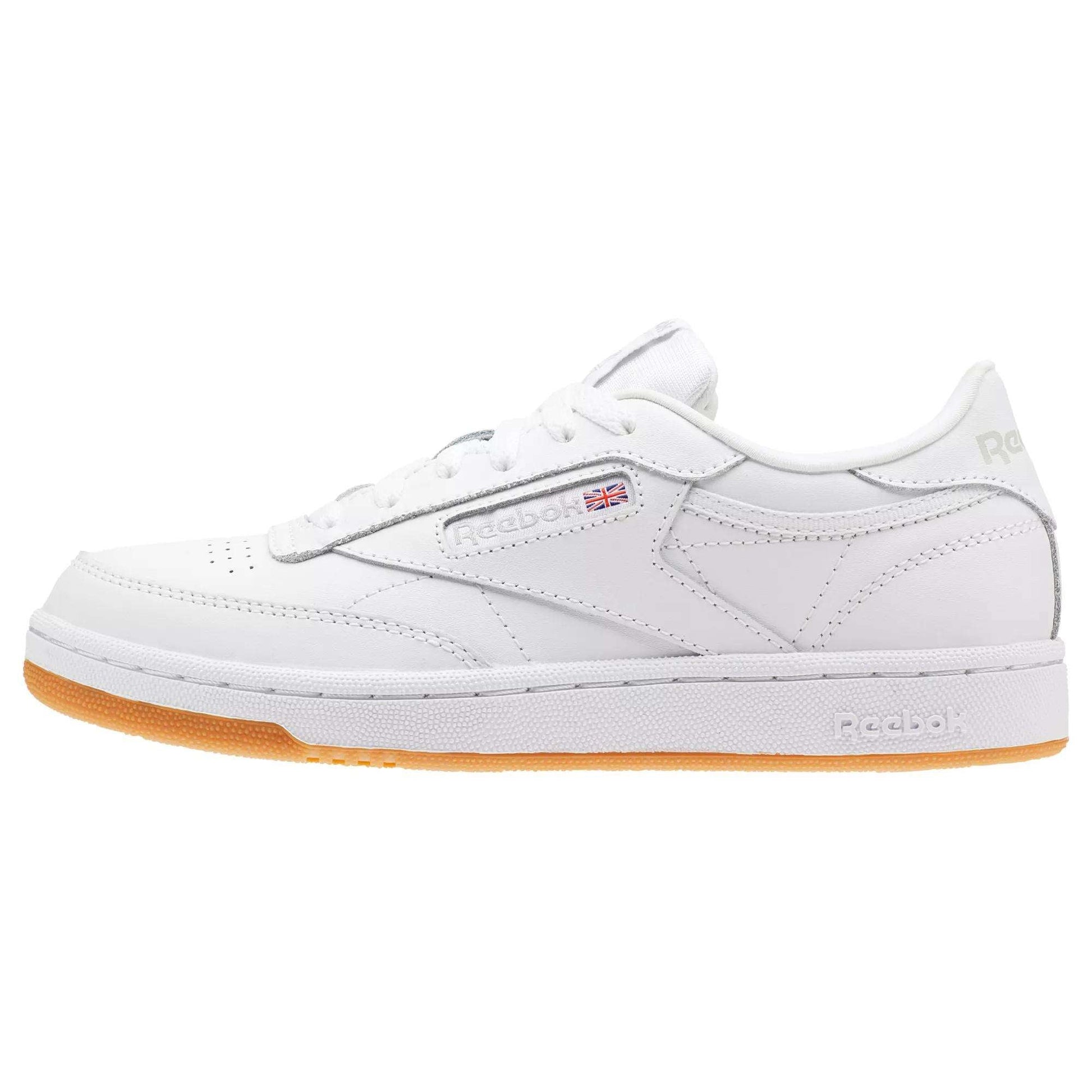 The Reebok Kids' Club C Shoes - Grade School feature soft white leather uppers, minimal stitching, a subtle Union Jack flag on the side, and a light brown high-abrasion rubber outsole.