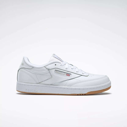 The Reebok Kids' Club C Shoes - Grade School feature soft white leather uppers, a gum sole, side branding, and perforated accents, displayed on a plain light gray background.