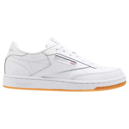 The Reebok Kids' Club C Shoes - Grade School feature a low-profile white design with soft leather uppers, white stitching, a gum rubber sole, Reebok branding, and a small Union Jack flag—offering classic court style and all-day comfort.