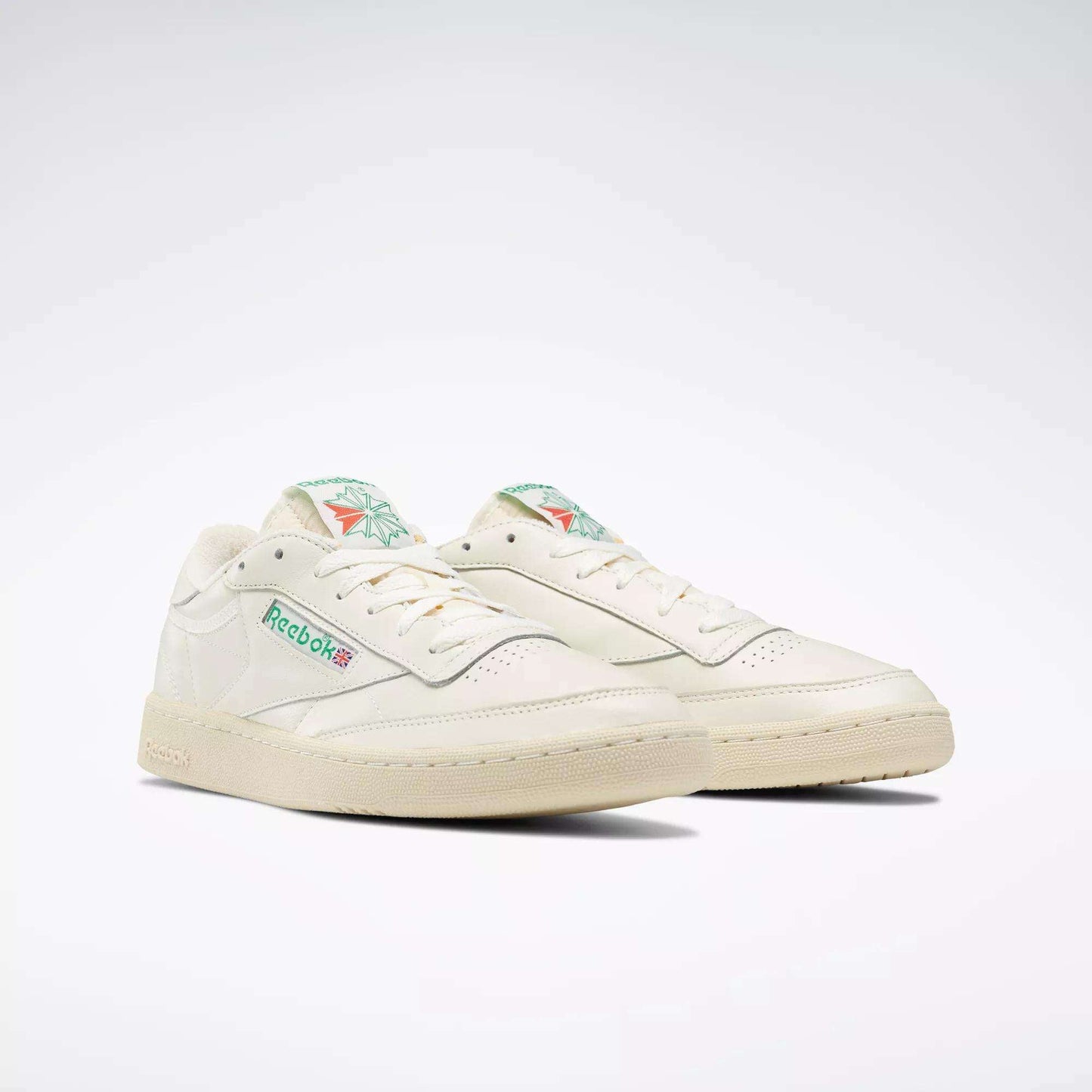 A pair of Reebok Club C 85 Vintage Shoes in off-white with green and pink accents, leather upper, and classic branding on the side and tongue, displayed against a plain white background.