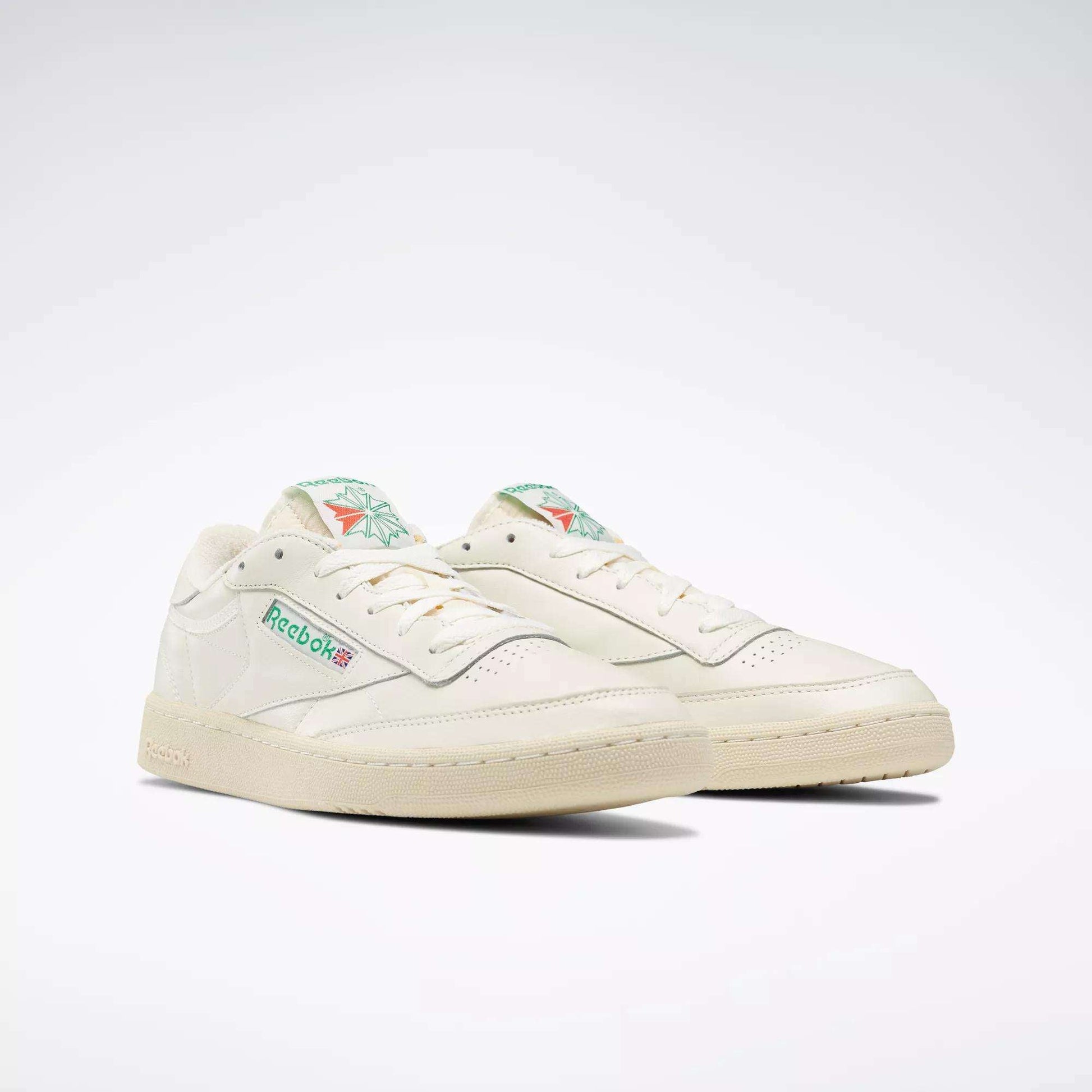 A pair of Reebok Club C 85 Vintage Shoes in off-white with green and pink accents, leather upper, and classic branding on the side and tongue, displayed against a plain white background.