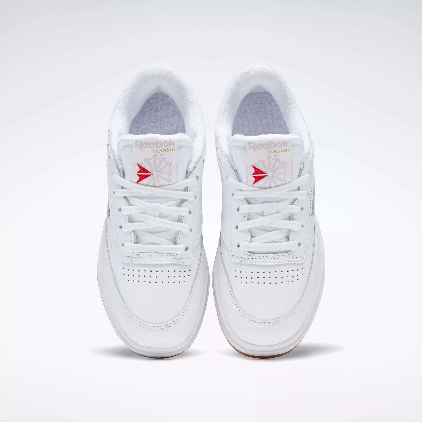 A pair of white Reebok Women's Club C Double Shoes with white laces, seen from above, featuring perforated toe details, a platform midsole, and Reebok branding on the tongue.