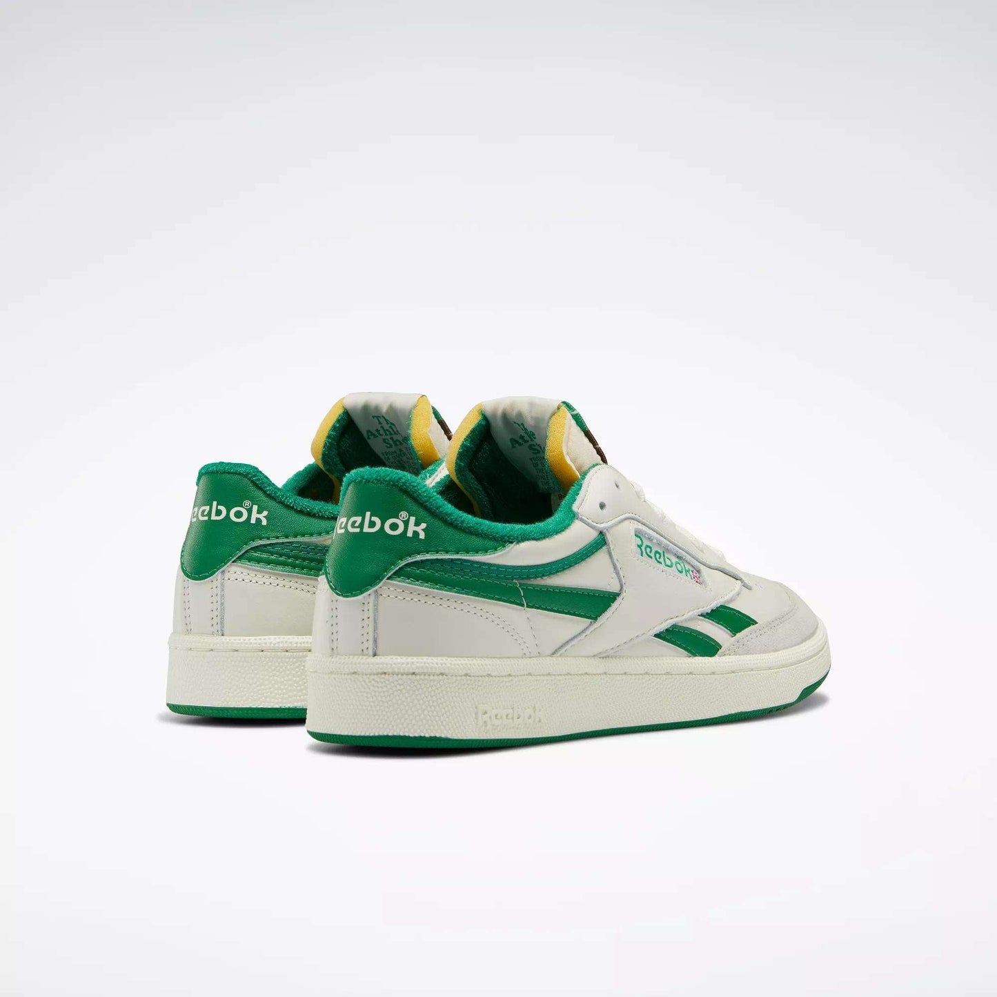 The Reebok Men's Club C Revenge Vintage Shoes, in white with green accents and branding, display a retro leather design and are set against a plain, light background.