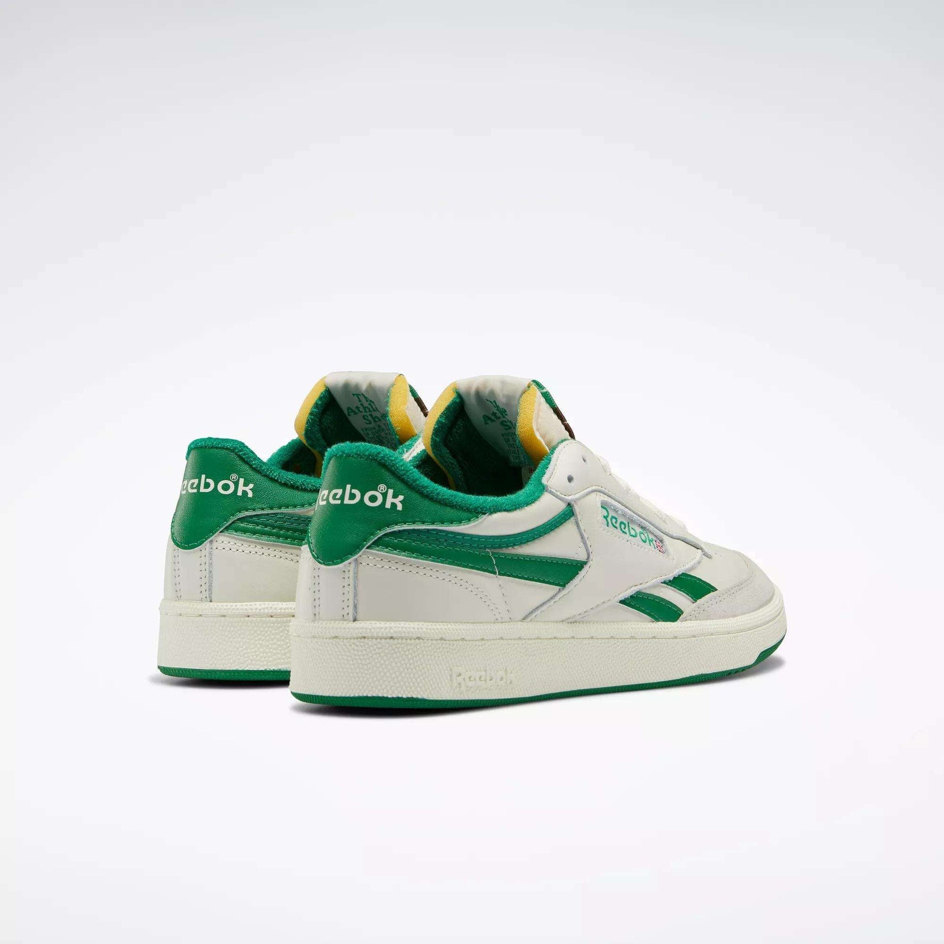 The Reebok Men's Club C Revenge Vintage Shoes, in white with green accents and branding, display a retro leather design and are set against a plain, light background.