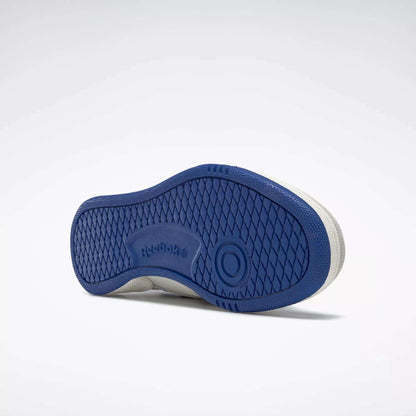 A single Reebok Men's Club C Revenge Vintage Shoe is shown on its side, revealing a textured blue rubber sole with diamond and circular patterns, plus "Reebok" embossed near the arch—highlighting its tennis-inspired style.