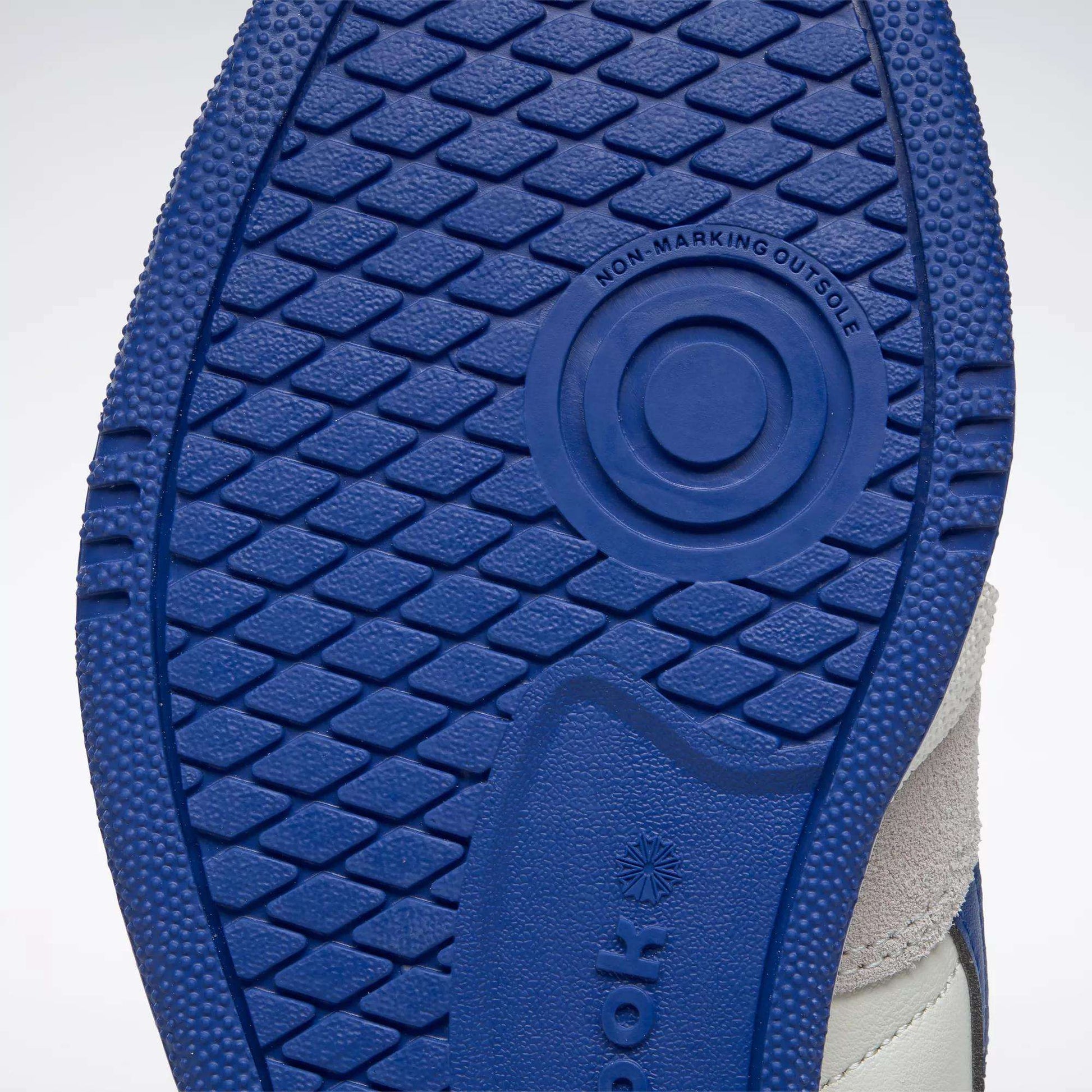 Close-up of the blue sole on Reebok Men's Club C Revenge Vintage Shoes displays a textured grip with "NON-MARKING OUTSOLE" visible, along with part of the upper and vintage-style leather.