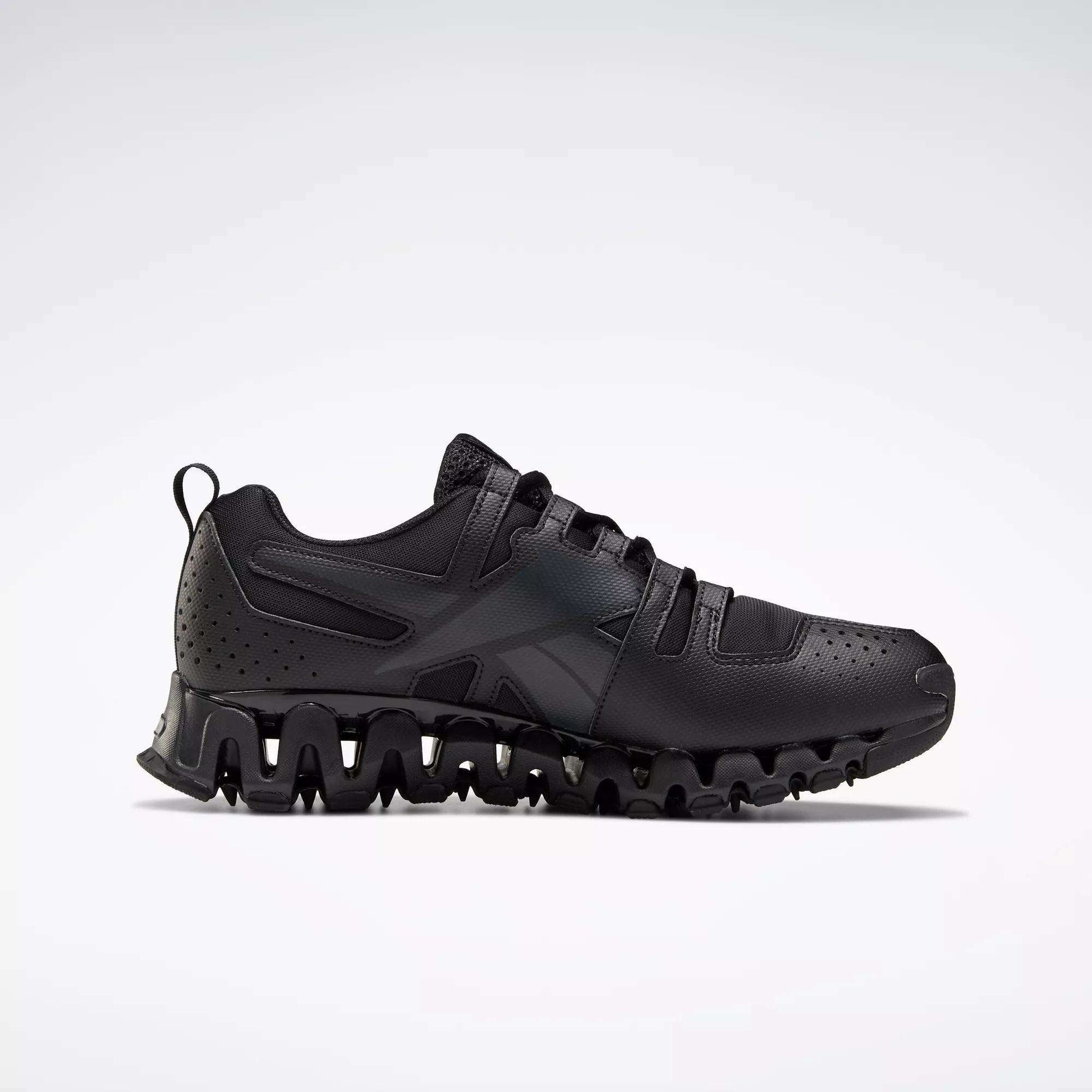 The Reebok Men's ZigWild Trail 6 Shoes is a black athletic sneaker with a wavy, textured sole, enhanced cushioning, perforated heel details, and black laces. Shown in side profile on a plain light background.
