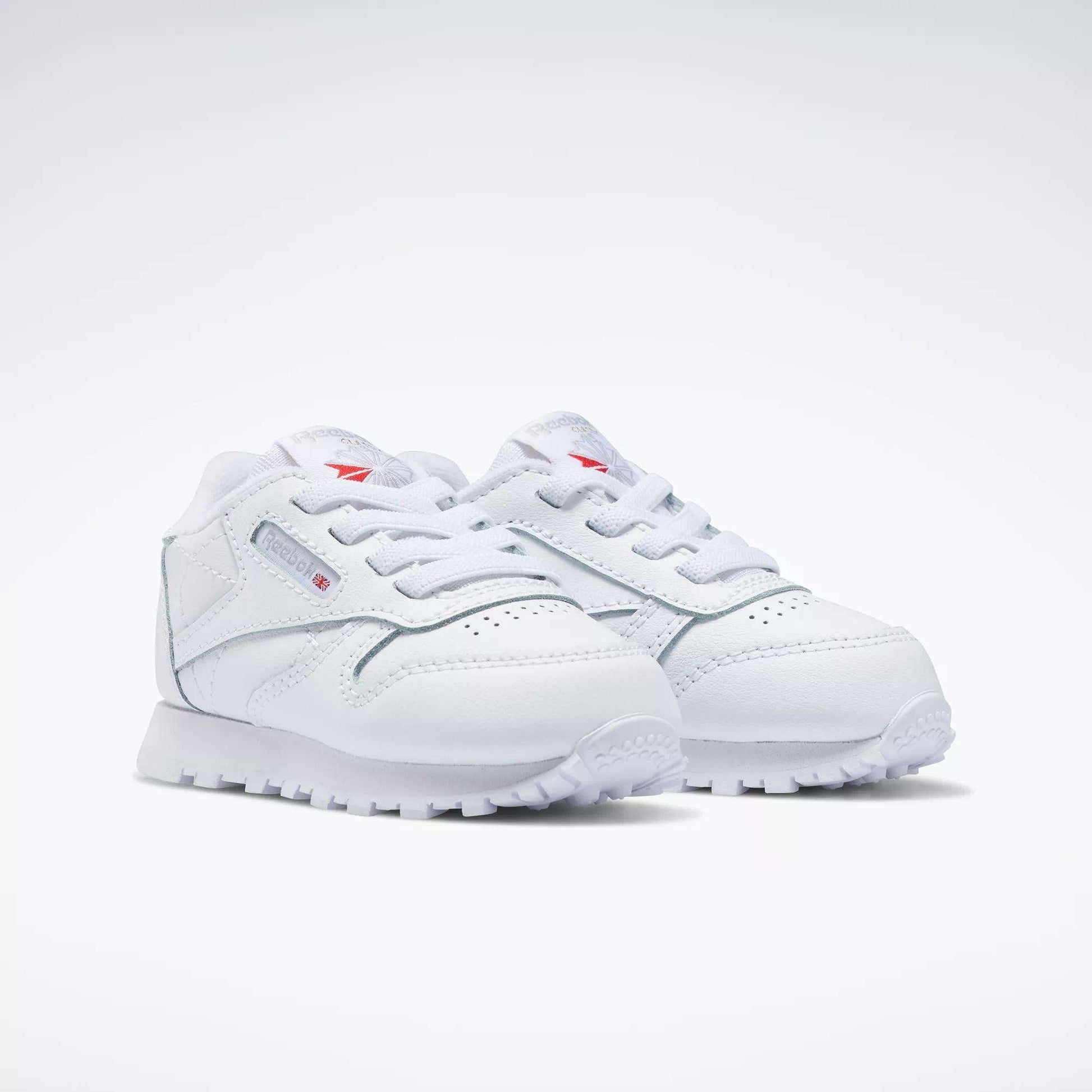 The Reebok Kids' Classic Leather Shoes – Baby & Toddler—white with laces and subtle side and tongue branding—are shown on a plain white background, offering timeless style for little ones.