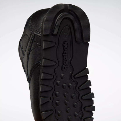 Close-up of the black rubber sole on Reebok Kids' Classic Leather Shoes for babies and toddlers, featuring a textured tread pattern and the embossed Reebok logo—an iconic detail on classic sneakers.