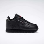 The Reebok Kids' Classic Leather Shoes - Baby & Toddler are displayed in side profile, featuring a black design with matching laces and sole, plus subtle brand details on the side and tongue against a white background.