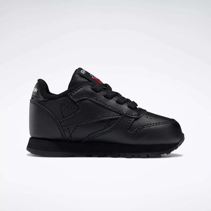 The Reebok Kids' Classic Leather Shoes - Baby & Toddler feature a black leather design with black laces and sole, shown in side profile on a white background for a timeless old-school sneaker look.