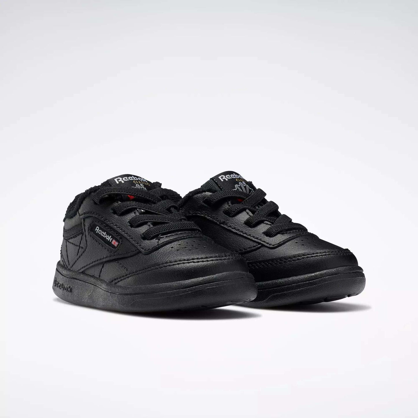 A pair of Reebok Kids' Club C Shoes for babies and toddlers, featuring a low-cut black leather design with laces and brand logos on the side and tongue, displayed on a plain white background.