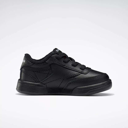 A single black Reebok Kids' Club C Shoe for babies and toddlers, featuring soft leather, black laces, and stitching details, is displayed in side profile against a plain white background.
