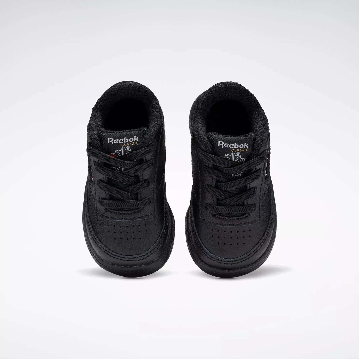 A pair of Reebok Kids' Club C Shoes for babies and toddlers, in black soft leather, are displayed side by side on a plain white background, viewed from above.