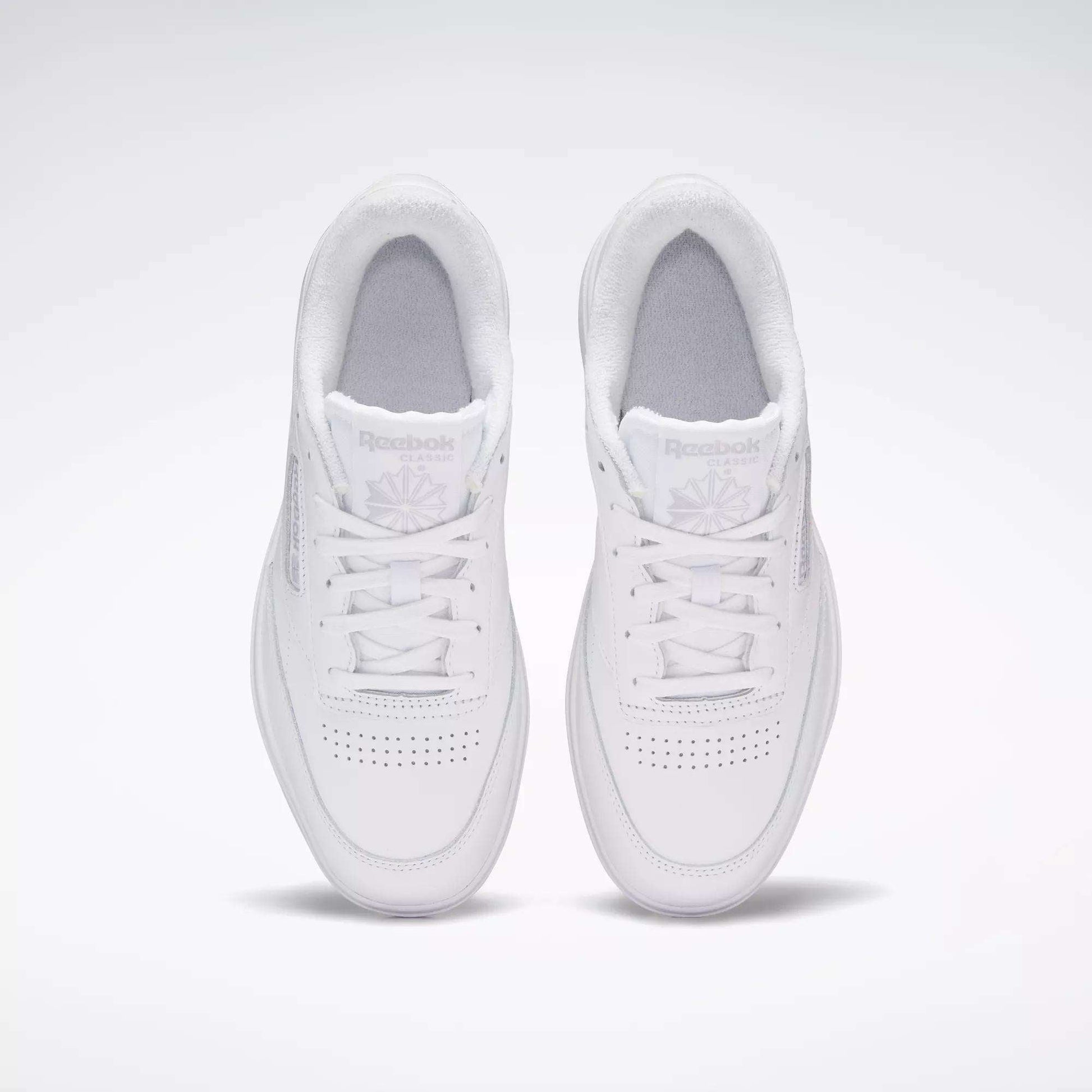 A pair of Reebok Women's Club C Double Shoes in white, seen from above on a light background, highlighting the perforated toe and Reebok logo on each tongue.