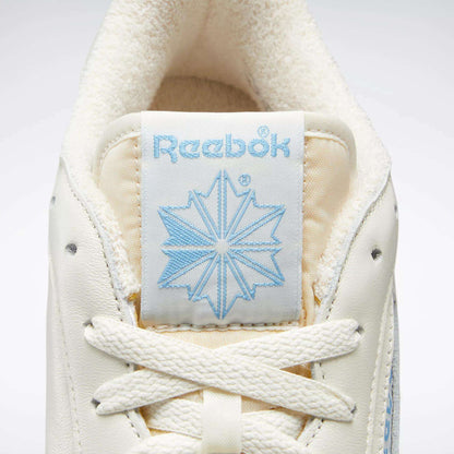Close-up of a Reebok Club C 85 Vintage Shoes' tongue, featuring a light blue Reebok logo and star, off-white laces, plush inner lining at the top, and premium leather upper for a classic court-inspired look.