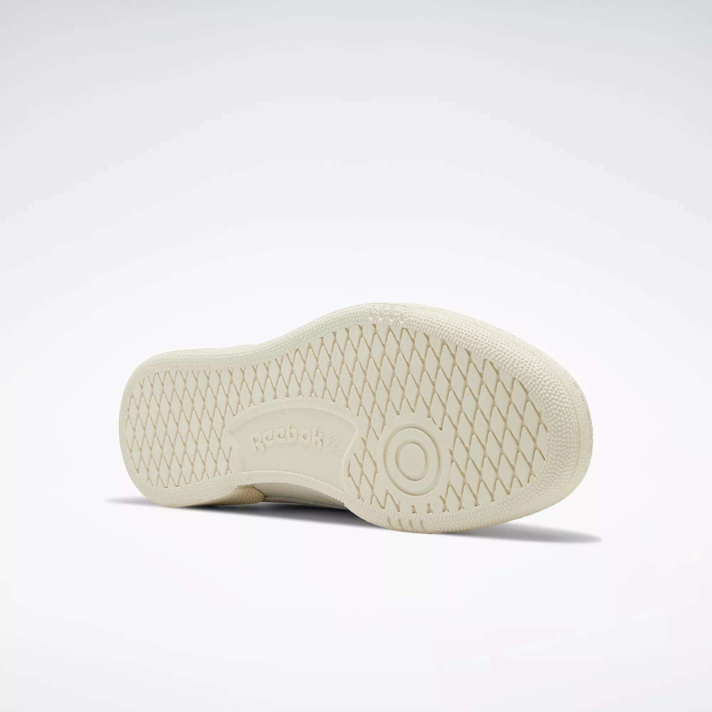 The image displays the sole of a beige Reebok Club C 85 Vintage Shoe against a light background. The sneaker features a diamond-patterned tread with the Reebok logo and a circular design in the center.