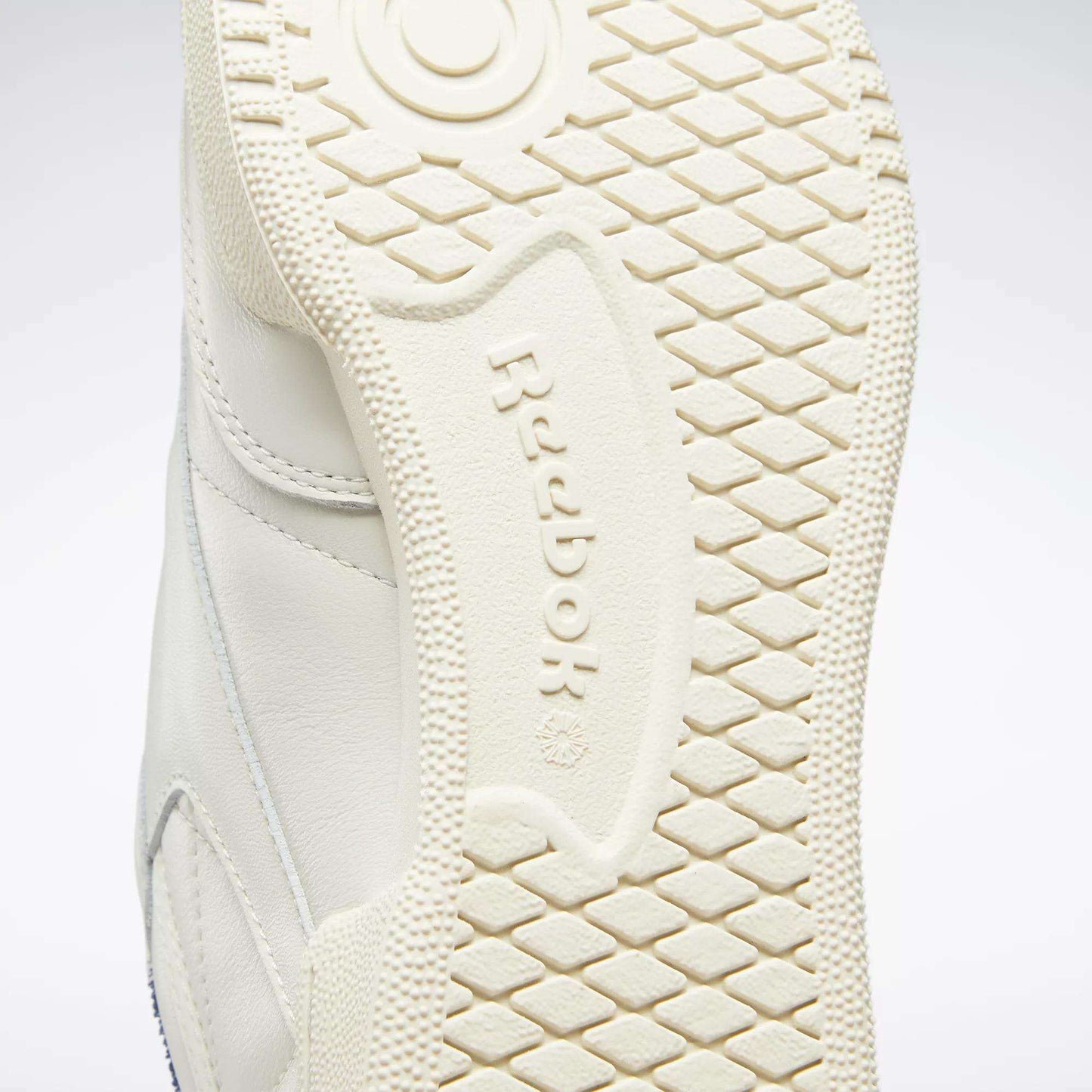Close-up of the off-white rubber sole on Reebok’s Club C 85 Vintage Shoes, highlighting the textured tread pattern and embossed Reebok logo at the center.