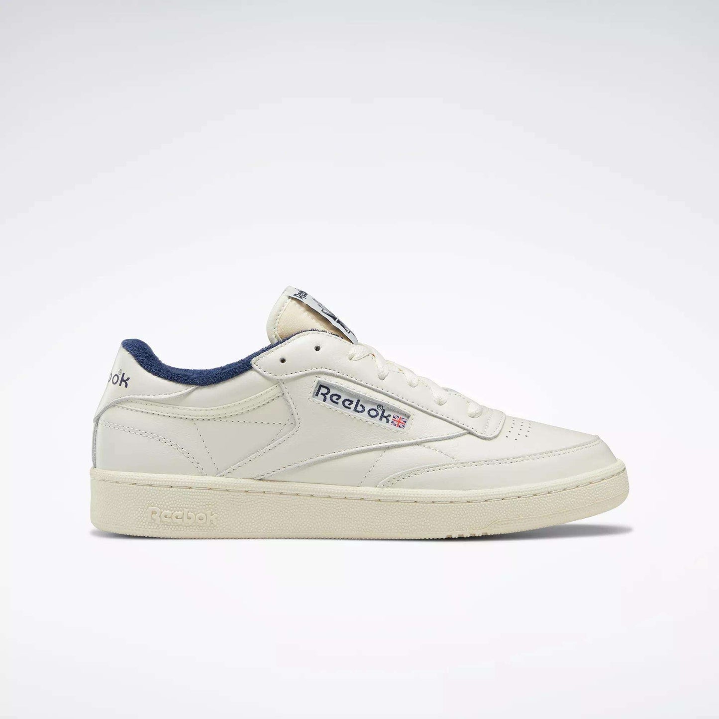 The Reebok Club C 85 Vintage Shoes feature a cream leather upper, navy accents, side branding, and a classic low-top design, displayed against a plain white background.