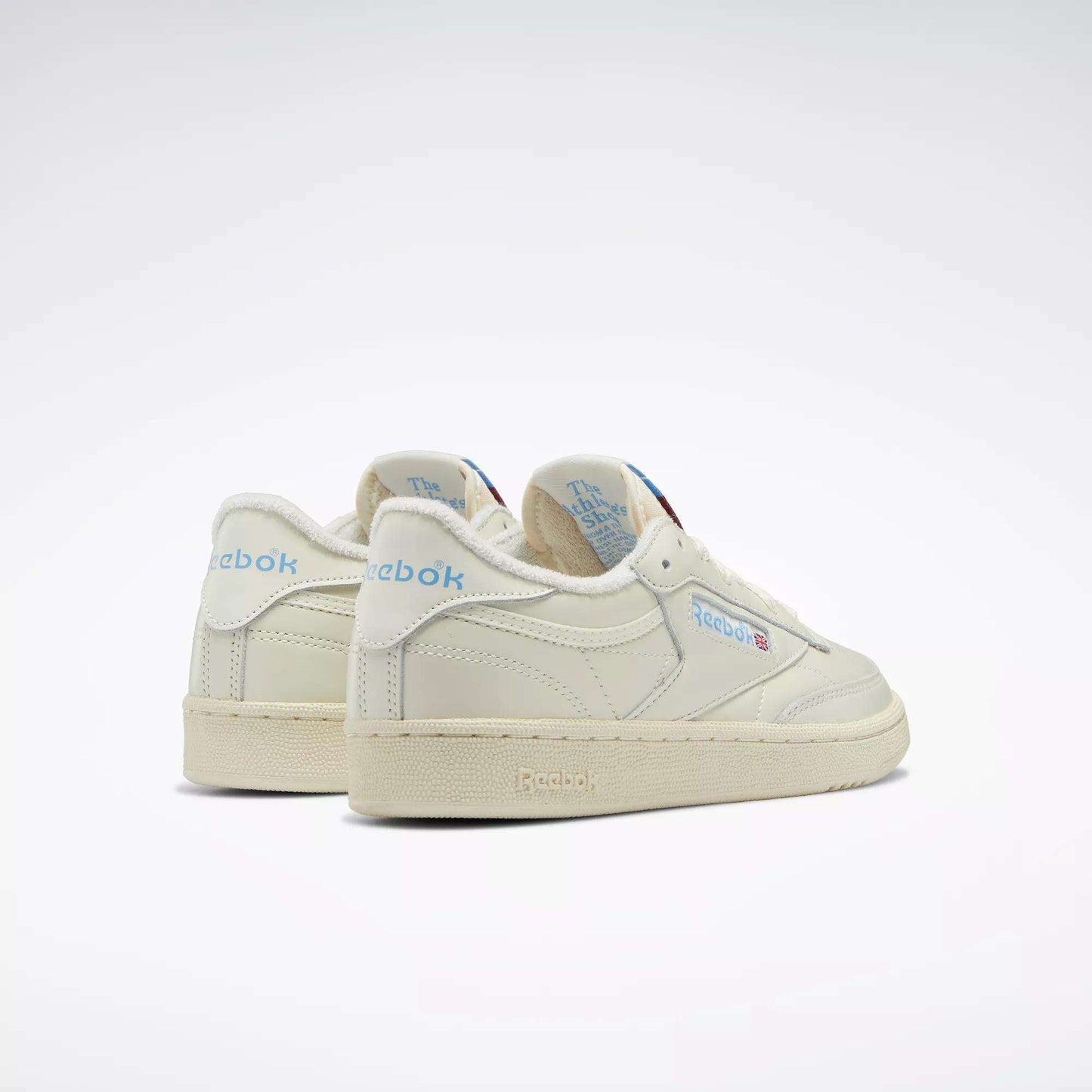A pair of Women's Club C 85 Vintage Shoes by Reebok in off-white, featuring blue Reebok logos and branding, displayed from back and side angles on a plain white background.