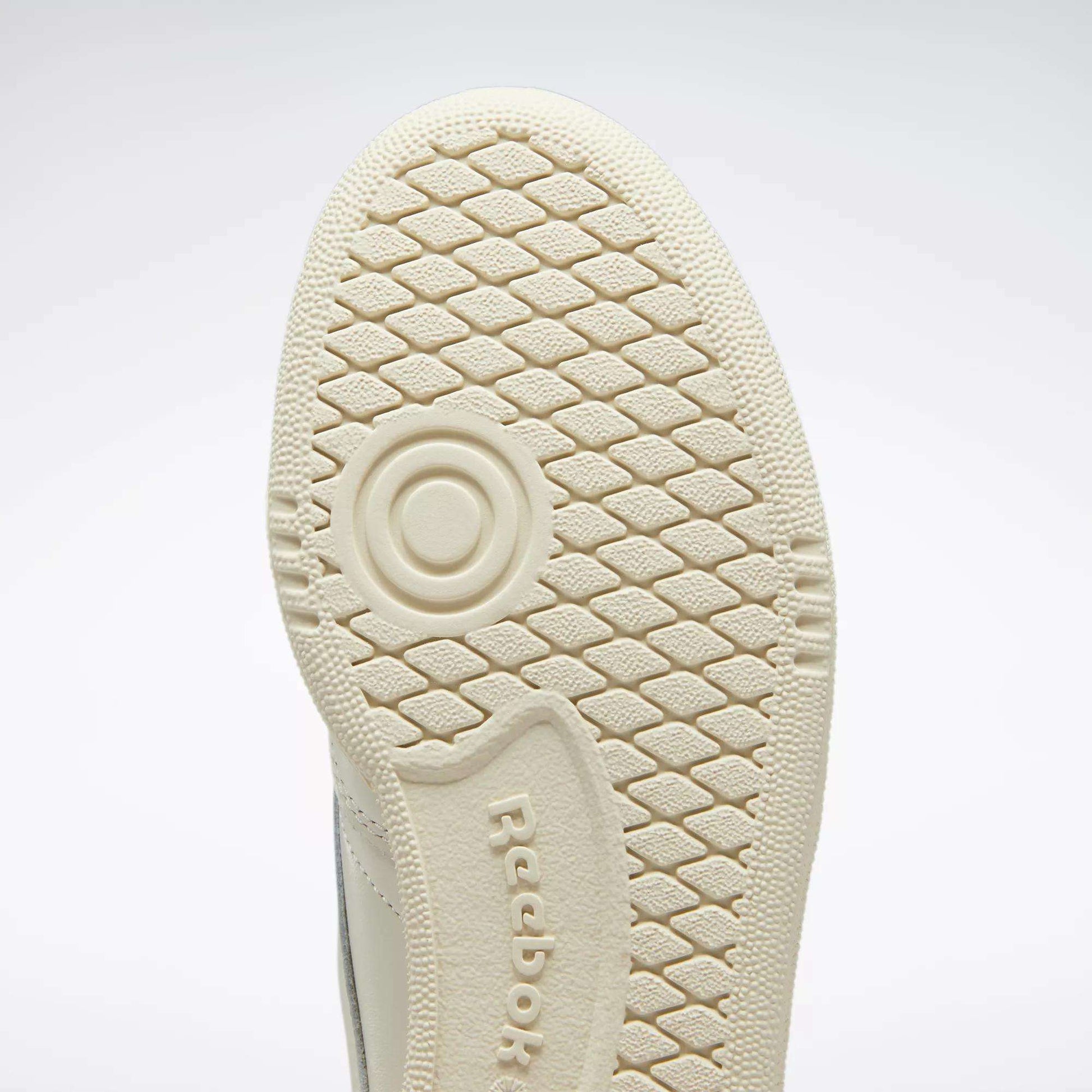Close-up of the sole on Reebok Women's Club C 85 Vintage Shoes, featuring a beige color, textured honeycomb-like tread pattern, and an embossed Reebok logo at the center.