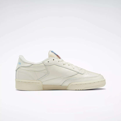 The Reebok Women's Club C 85 Vintage Shoes, shown in side profile against a white background, feature a cream color, low-top design, visible stitching, and classic rubber sole inspired by tennis styles.