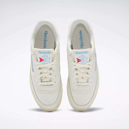 A pair of Reebok Women's Club C 85 Vintage Shoes in off-white, seen from above, with blue Reebok logos on the tongues and insoles, white laces, and subtle perforations on the toe boxes.