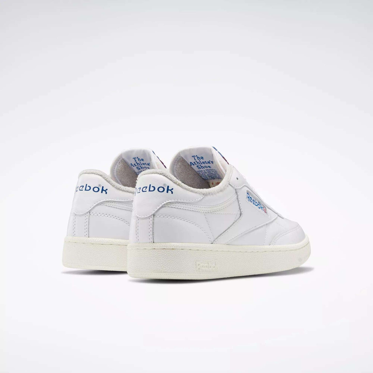 A pair of Reebok Club C 85 Vintage Shoes in white with blue branding and lightweight cushioning, featuring The Animals Observatory text on the inner heel, displayed against a plain, light background.