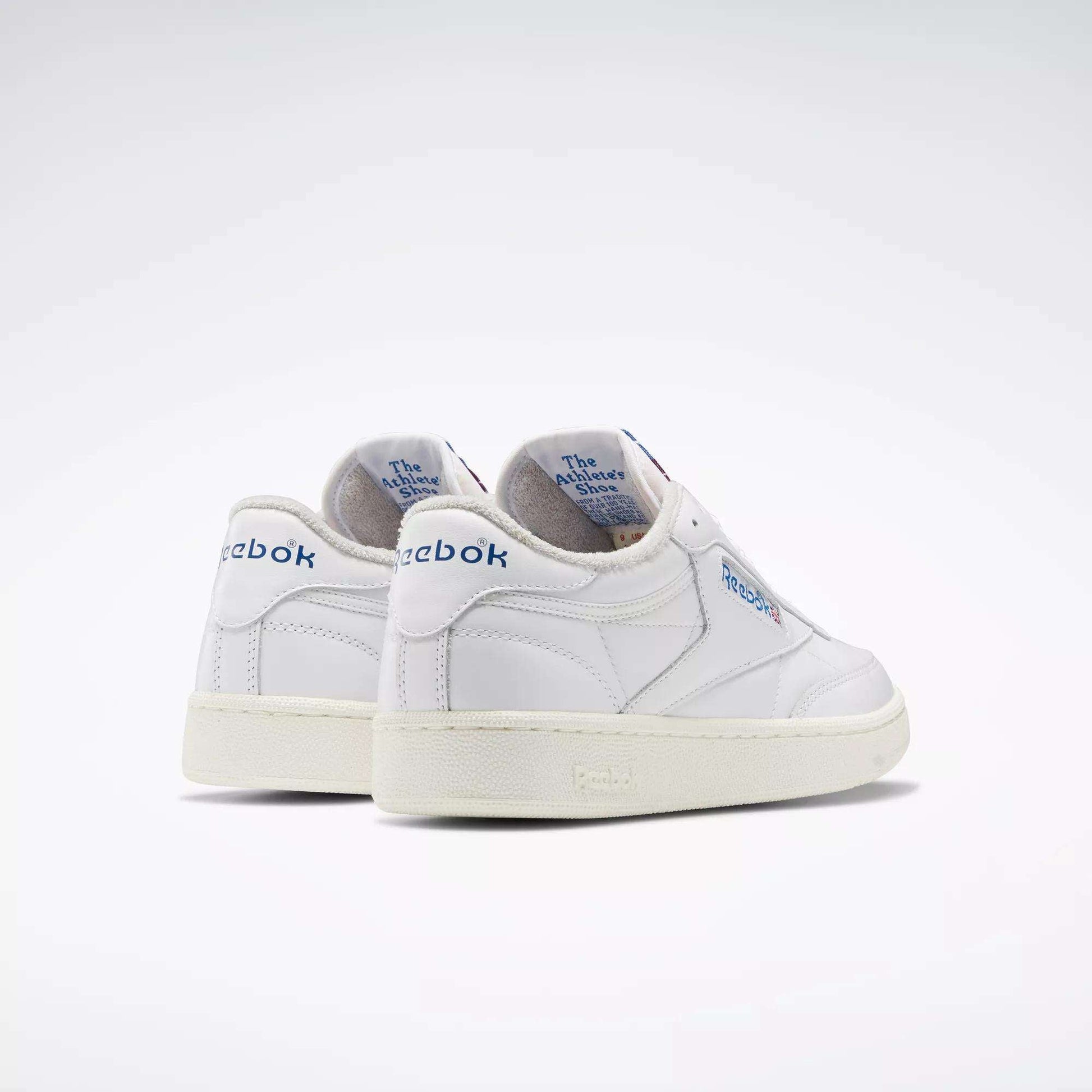 A pair of Reebok Club C 85 Vintage Shoes in white with blue branding and lightweight cushioning, featuring The Animals Observatory text on the inner heel, displayed against a plain, light background.