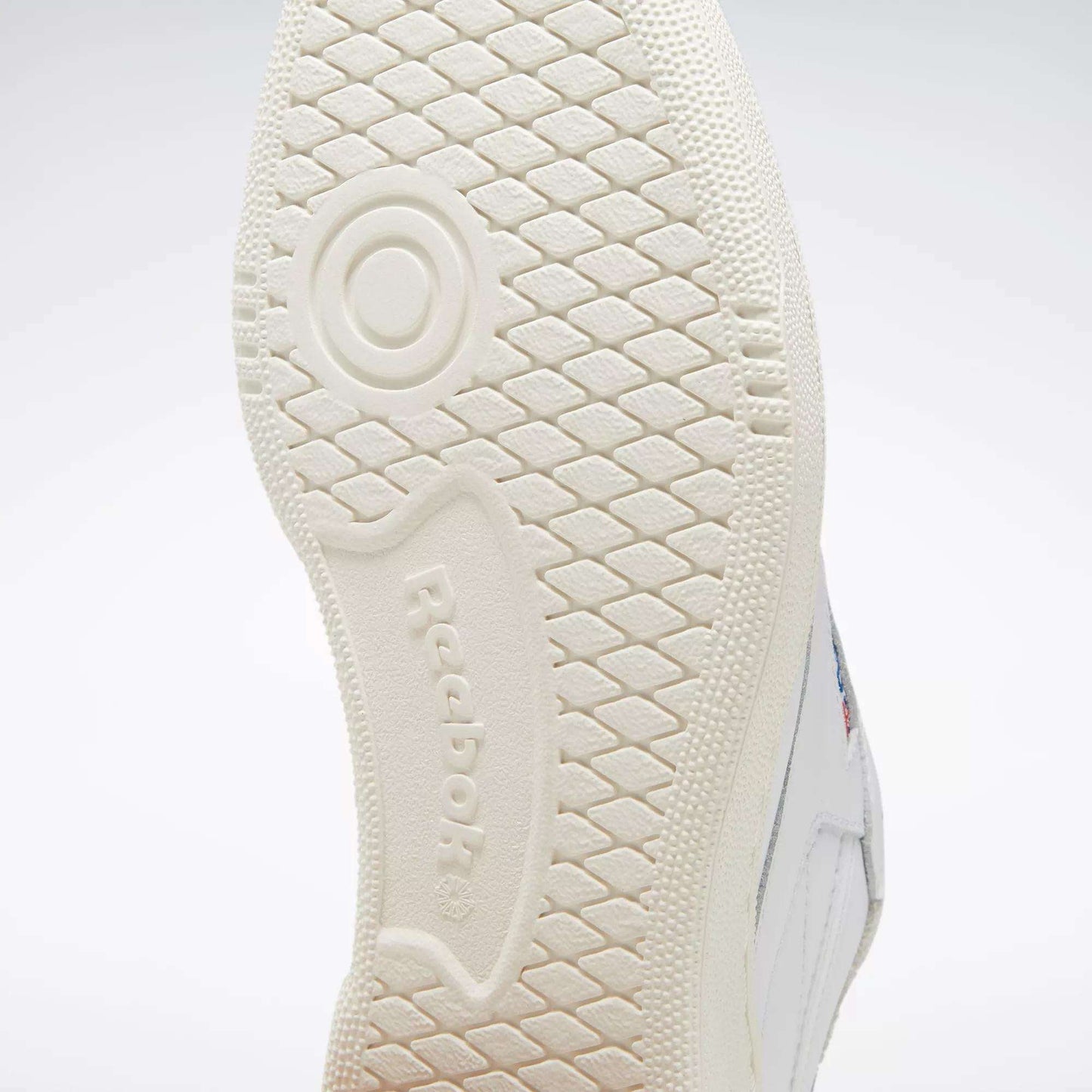Close-up of the textured sole on white Club C 85 Vintage Shoes by Reebok, showcasing the brand name and a circular tread pattern—ideal for court classics with lightweight cushioning.
