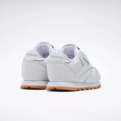 The Reebok Kids' Classic Leather Shoes - Baby & Toddler in white with light gray accents and gum soles are shown from the back and side on a plain white background. Ideal for toddlers who enjoy timeless style.