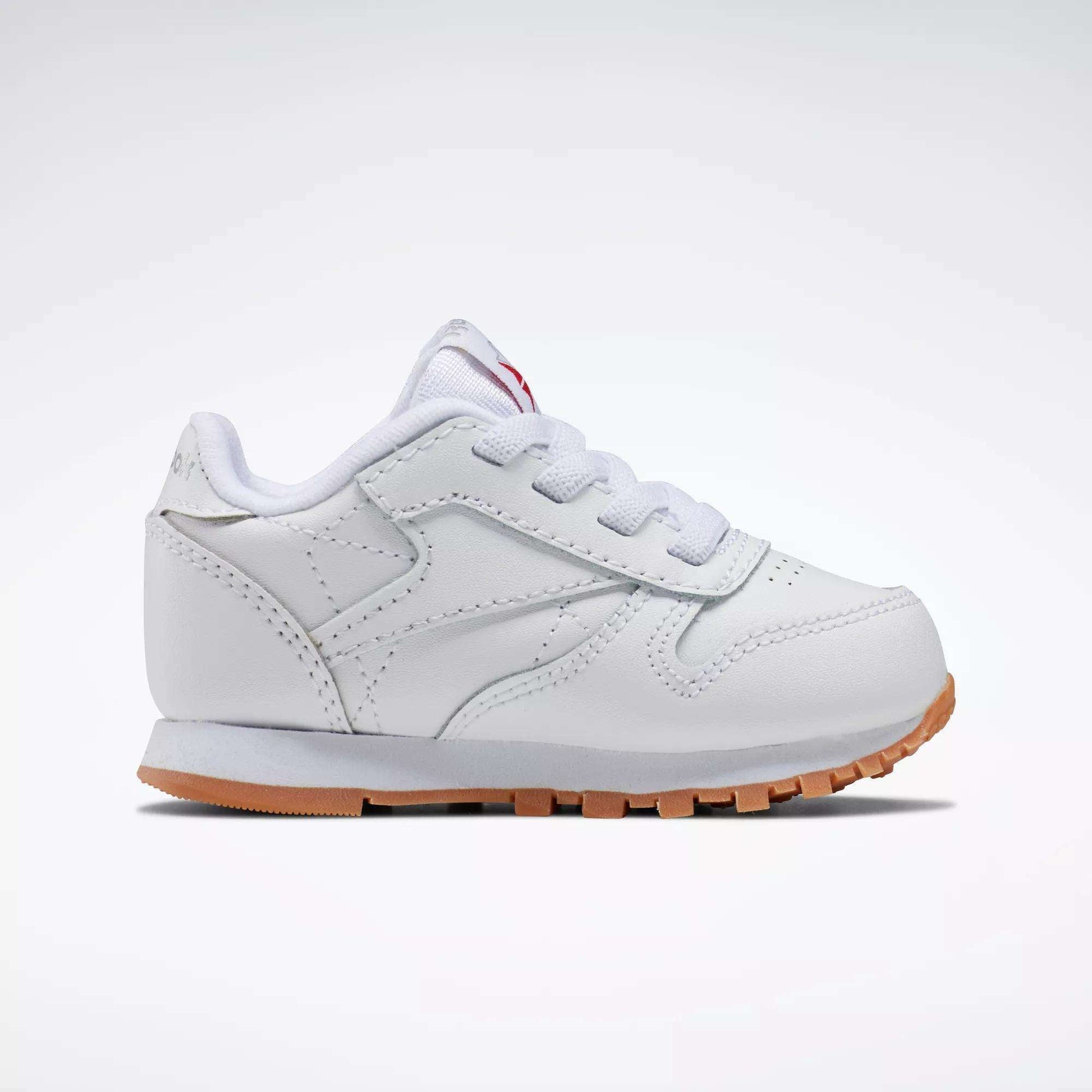 The Reebok Kids' Classic Leather Shoes for babies and toddlers feature white laces and a light brown rubber sole, shown against a plain white background.