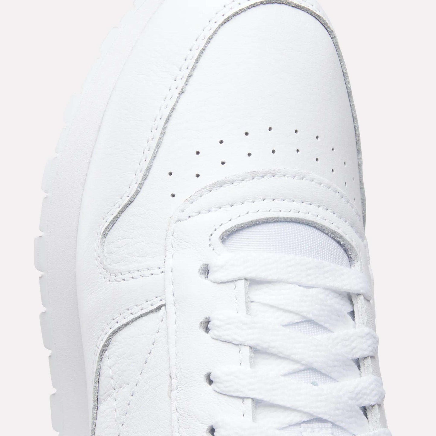 Close-up of the upper part of the Reebok Classic Leather Shoes, featuring laces, detailed stitching, breathable perforations, a durable leather upper, and a glimpse of the textured rubber sole for a retro-inspired look.