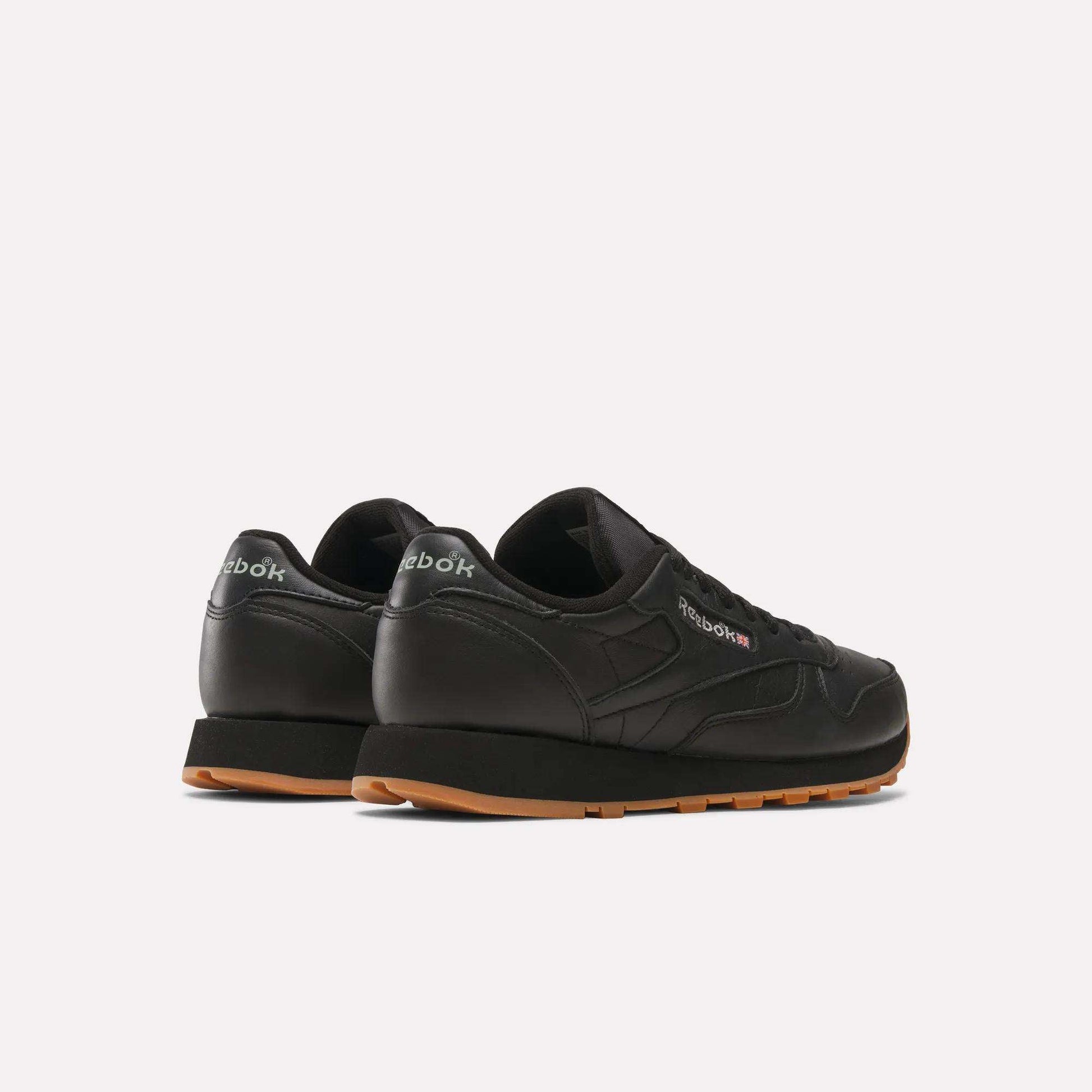 A pair of Reebok Classic Leather Shoes with durable black leather uppers and brown rubber soles, shown from the back and side on a light background. The retro Reebok logo appears on the heel and side.
