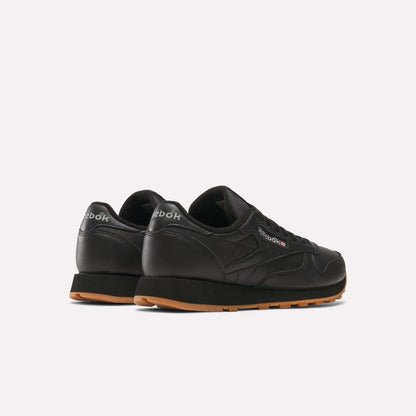 A pair of Reebok Classic Leather Shoes with durable black leather uppers and brown rubber soles, shown from the back and side on a light background. The retro Reebok logo appears on the heel and side.